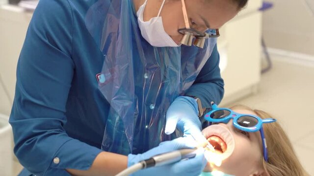 little girl with oral dilator at dentist's appointment. polishing of teeth