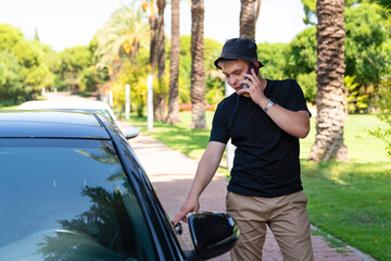 a modern young guy in simple black clothes and a panama hat is talking on the phone and getting...