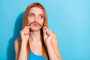 Portrait of attractive funny cheerful red-haired girl making mustache having fun isolated over vibrant blue color background