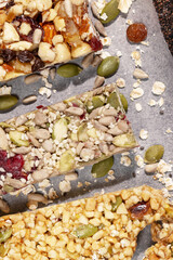 Different kind of granola cereal bars with nuts, seeds, oats, berries,raisins and dry fruits on a white pergament paper. Protein muesli bars. Granola superfood. Natural energy healthy snack