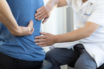 The doctor is diagnosing the patient's back pain. A male with back pain sees a doctor for treatment.