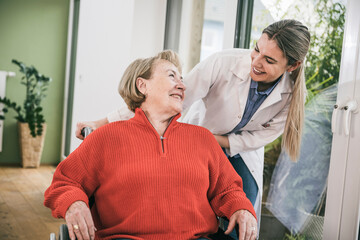 Disabled woman smiling at nurse standing behind