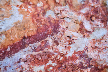 Natural stone texture close up. Abstract background with a pronounced textured pattern of red shades.
