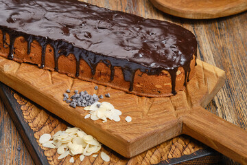 Chocolate bundt or panettone cake decorated chocolate glaze on a wooden brown kitchen boards with almonds and grains of chocolate. Shallow depth of field