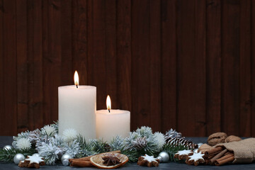 Weihnachtshintergrund: Weiße Kerzen mit Tannenzweigen vor einer Holzwand.