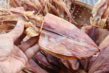 New round dried squid large seafood clean fresh in hand Thai delicious food snacked on wicker...
