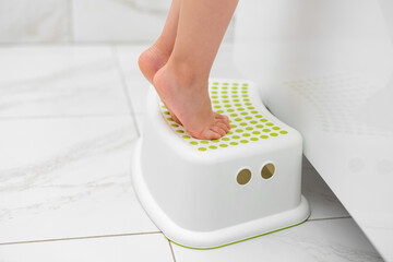 Small legs stand on a special children's bath stand.