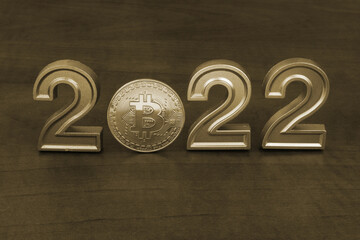 Bitcoin cost and future prognosis in 2022. Bitcoin coin and numbers 2022 on table.