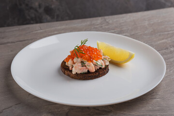Toast skagen - classic Swedish appetizer. Sandwiches with shrimps and caviar on dark table. Isometric style. Nordic cuisine. Selective focus.
