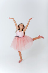 Happy little girl in pink dress jumping on a white background. Space for text. 