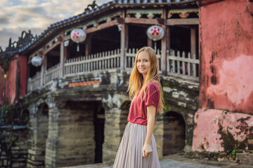 Woman tourist on background of Beautiful Japanese Bridge in Hoi An. Vietnam. Vietnam opens to...