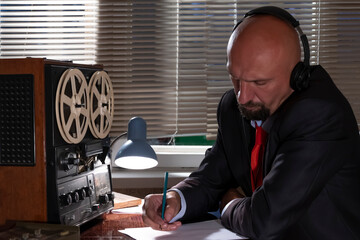 An FBI or KGB secret agent eavesdrops on headphones and records the conversation on a reel-to-reel...
