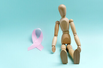 Pink ribbon and wooden mannequin. Health concept pink ribbon. Breast cancer.