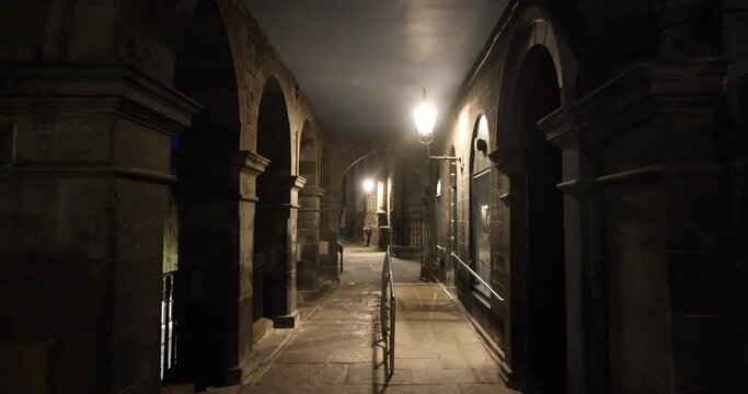 Empty Victoria Street in Edinburgh on a quiet night with traditional shops, the street lights cast gloomy shadows on the buildings lining the dark street. After midnight, the old town becomes empty