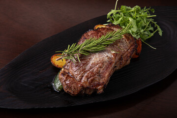 Grilled striploin steak on black dish. steak with fried potatoes and vegetables, Grilled beef steak with rosemary