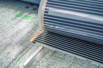 A roll of film underfloor heating lies on the insulation
