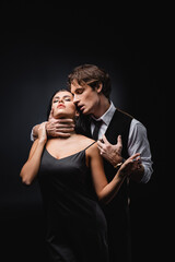 passionate man choking submissive girlfriend in slip dress on black. - obrazy, fototapety, plakaty
