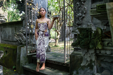 Balinese girl in a Hindu temple in Bali with incense sticks dressed in traditional dress. 