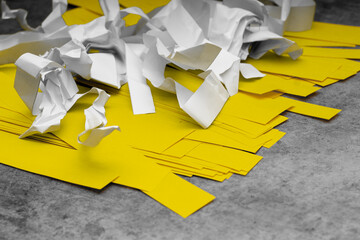 scraps of white crumpled paper and smooth yellow paper on a gray scuffed background; problems of recycling and reuse of paper