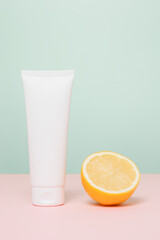 White tube for face cream, lotion or toiletry with sliced lemon, care cosmetics with vitamin c. Mockup unbranded cream bottle, mint color background