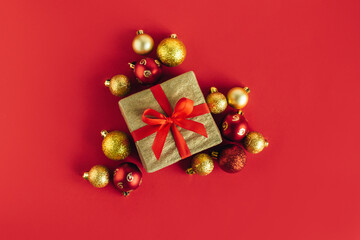 Gift box with  red and golden balls on a red background. Holiday concept.