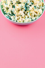 Bowl of sweet popcorn isolated on a pink background, with copy space