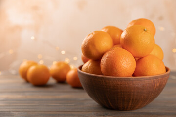 Orange tangerine or clementine fruits in a clay plate, on a tree background.
