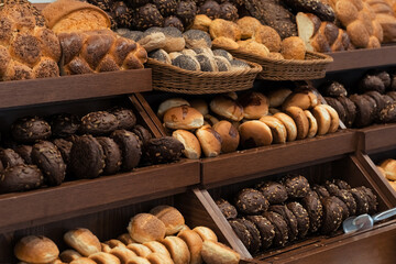 Breakfast lines of zopf or züpfe bread with sesames,  rye buns with sunflower seeds and white wheat buns with poppy seeds in wooden trays at the hotel restaurant.