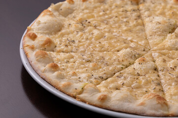 Focaccia pizza with cheese on white dish on a dark wooden table