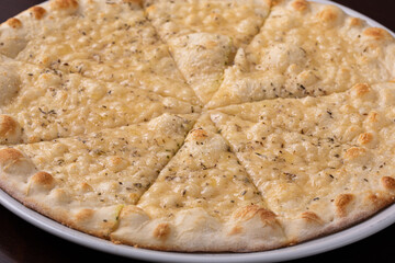 Focaccia pizza with cheese on white dish on a dark wooden table