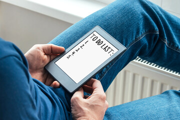 Modern gray tablet with to do list in man hands at home by the window