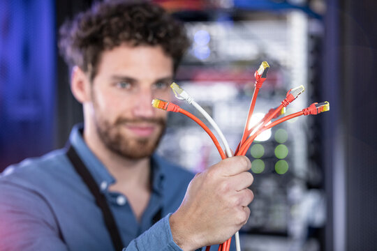 Male IT engineer holding patch cord cables in server room