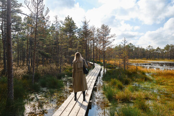 A woman walks along a scenic wooden decking nature trail in Lahemaa National Park in Estonia. The...