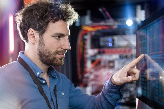 Male IT professional touching computer screen in data center