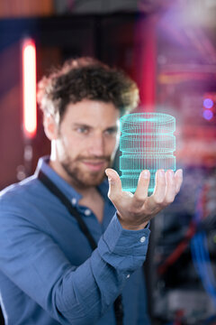 Male IT professional holding hologram of database in server room