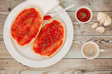 Pan con tomate y aceite de oliva, ajo y orégano, una taza de café, desayuno tradicional de España, sobre mesa de madera, visto desde arriba