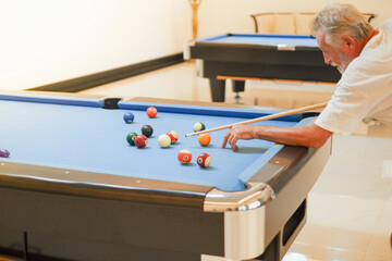 Portrait caucasian older, senior man playing billiards on pool table