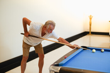 Portrait caucasian older, senior man playing billiards on pool table