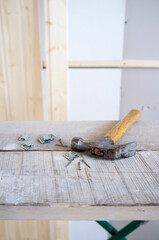 Hammer and nails lie on the scaffolding, against the background of a wall made of wooden slats. Work process. Home renovation.