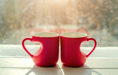 heart shaped mugs with tea on the background of a window in winter
