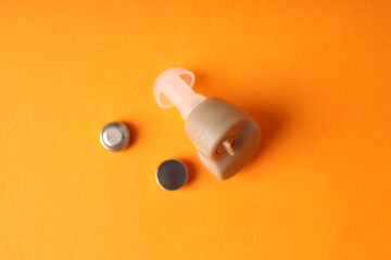 Concept of health care with hearing aid on orange background