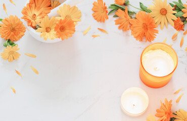 orange marigold  flowers with burning candles   on white marble background