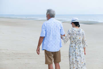 Portrait asia senior woman and caucasian old man relaxing together on the beach