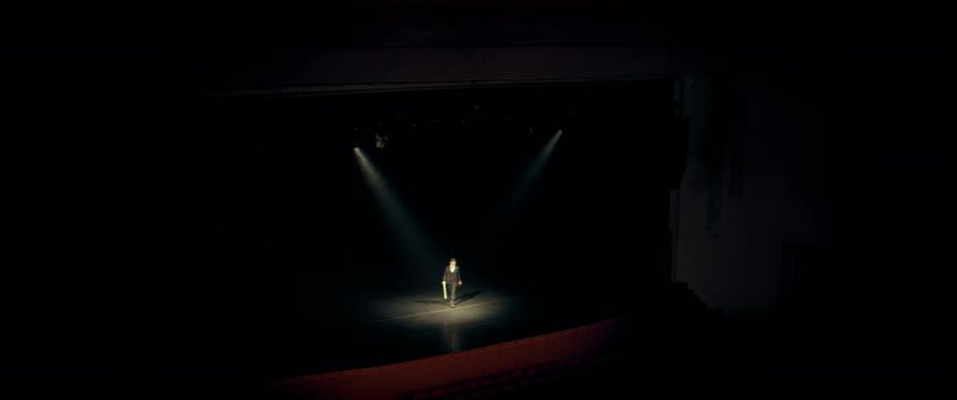 WID young aspiring musician violin player entering the stage of a large concert hall. Shot with 2x anamorphic lens