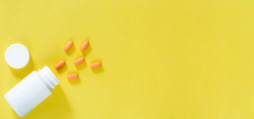 Pills and pill bottles on yellow background,Multicolor tablets and pills capsules from glass bottle on yellow background Heap of assorted various medicine tablets and pills. Health care Close-up Copy