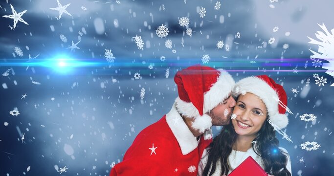 Composition of boyfriend kissing girlfriend in santa hat over snowy background, copy space