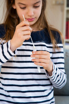 Girl putting nasal swab sample in test tube at home