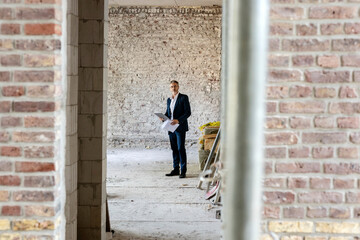 Male architect with digital tablet standing at construction site