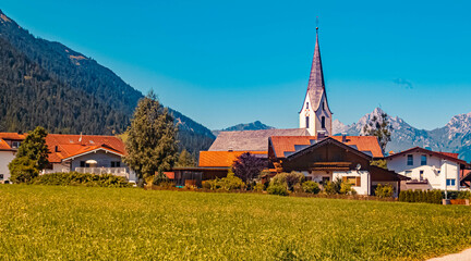 Fototapeta na wymiar Beautiful alpine summer view with a church and the alps near Reutte in the background at Bichlbach, Tyrol, Austria