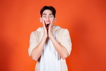 Surprised young man in pajamas on an orange background. Feelings and emotions.